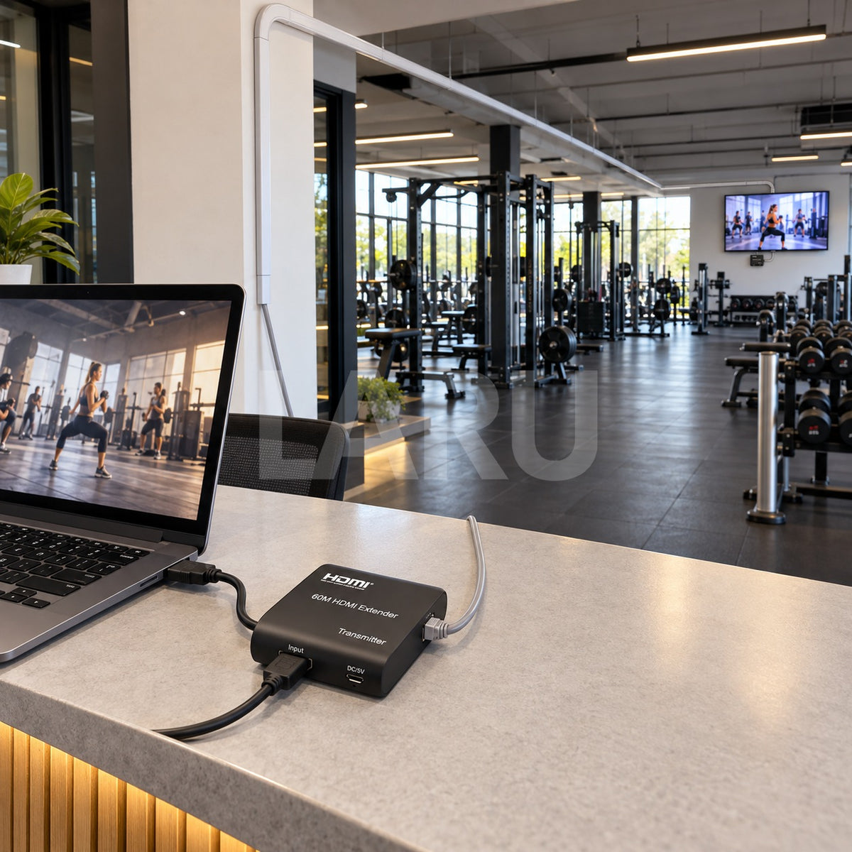 Extensor HDMI 60 m en uso: notebook en recepción y pantalla al fondo del gimnasio