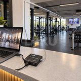 Extensor HDMI 60 m en uso: notebook en recepción y pantalla al fondo del gimnasio